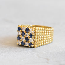 Load image into Gallery viewer, Angled view of an 18k yellow gold checkerboard ring showing the square diamond and sapphire face and the beaded granulated texture on the band.
