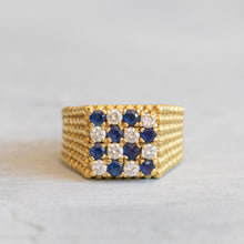 Load image into Gallery viewer, A gold band ring with a checkerboard style setting featuring blue sapphire and white diamonds