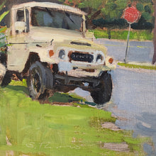 Load image into Gallery viewer, Close-up of white Land Cruiser near a stop sign with greenery and pavement.
