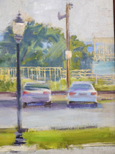 Load image into Gallery viewer, Close-up of roadway with parked cars, streetlight, and surrounding greenery.
