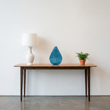 Load image into Gallery viewer, Computer-generated illustration: Orlando Zennaro Murano art glass vase with blue and black spiral pattern on a wooden console table beside a white lamp and a small plant
