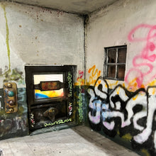 Load image into Gallery viewer, Close-up of interior corner featuring small furnace, tiled floor, and graffiti-covered walls.

